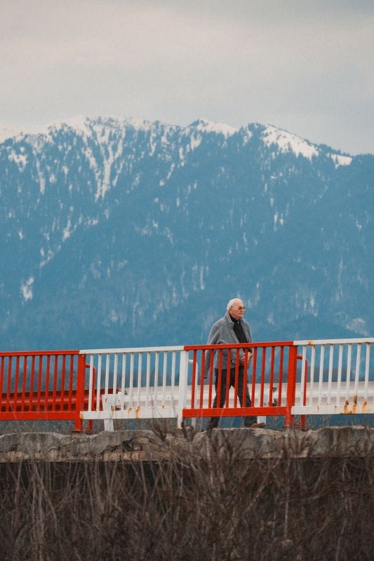 Un om plimbandu-se pe strazile Brasovului cu muntii Piatra Mare pe fundal, Martie 2026, foto de Alexandra Stefania Gal